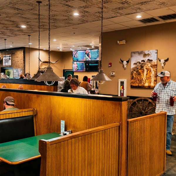 Yellowstone Steakhouse interior with wooden booths, diners, hanging lights, and Western-themed decor.